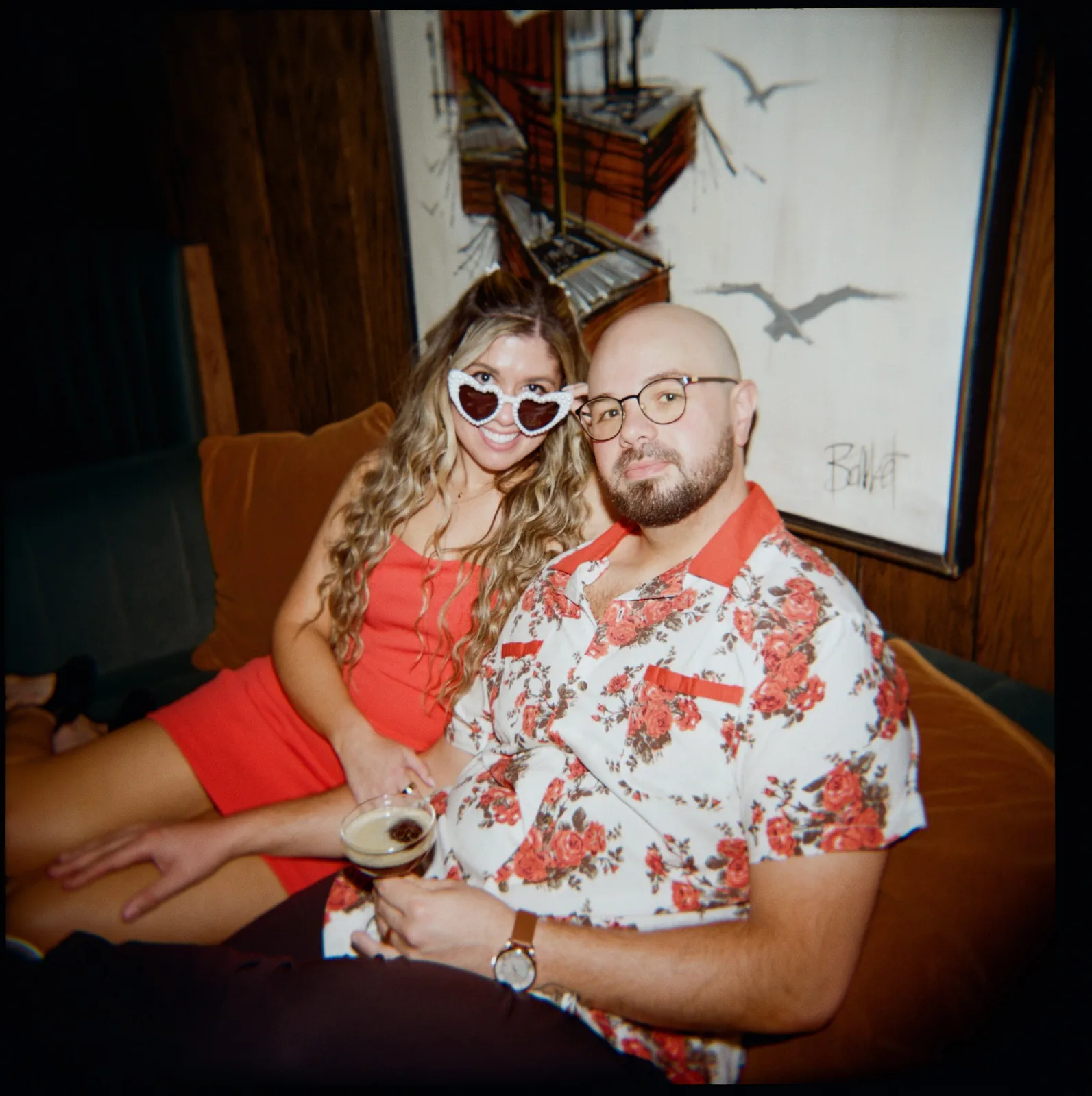 Nicole and Ian in a booth, Nicole in heart-shaped sunglasses