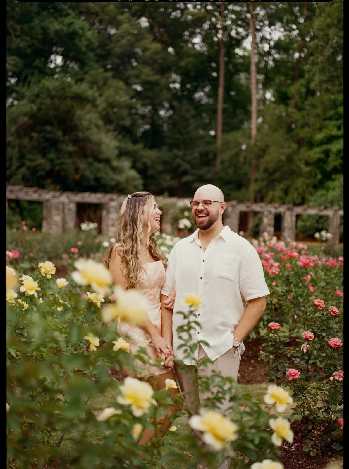 Nicole and Ian holding hands and laughing in the rose garden